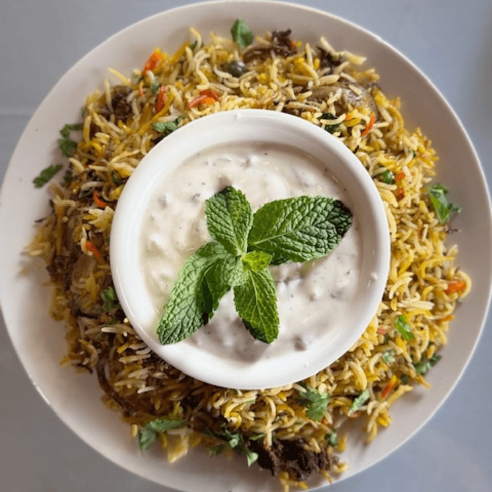 Royal India Restaurant's biryani with a side of raita, garnished with fresh mint.